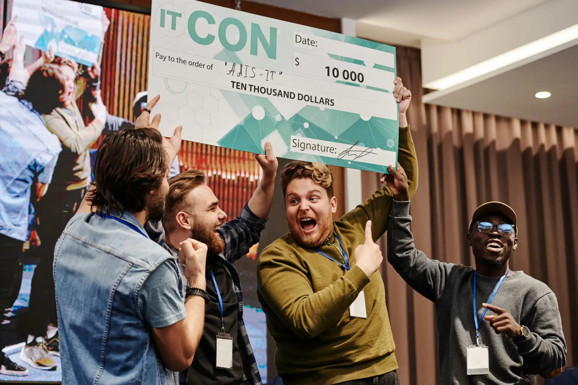 Excited business team celebrates winning a ten thousand dollar prize at a tech conference.
