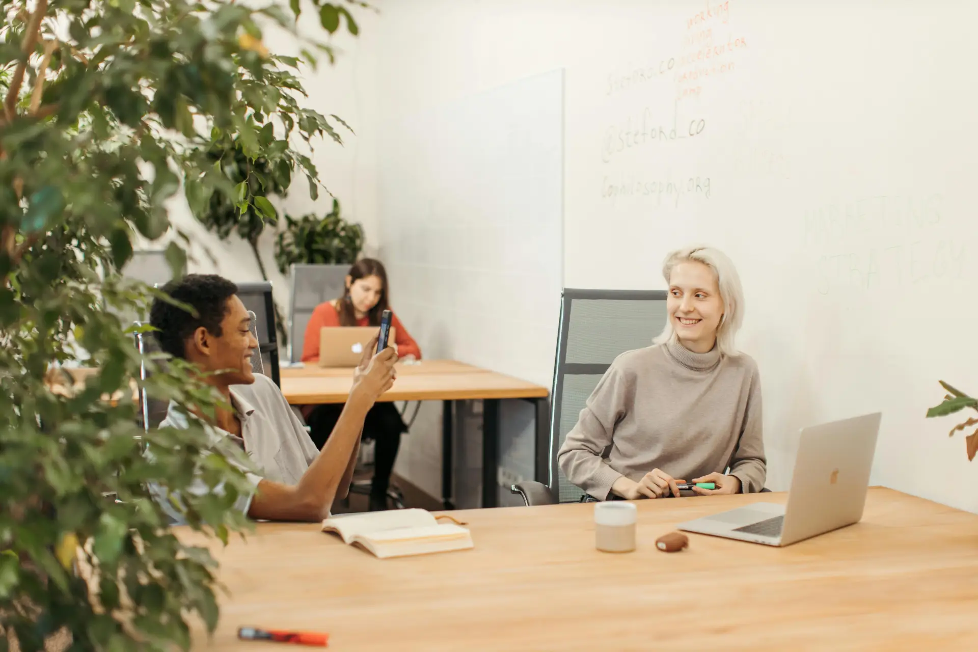 Three colleagues having a casual meeting in a bright, modern office space.
