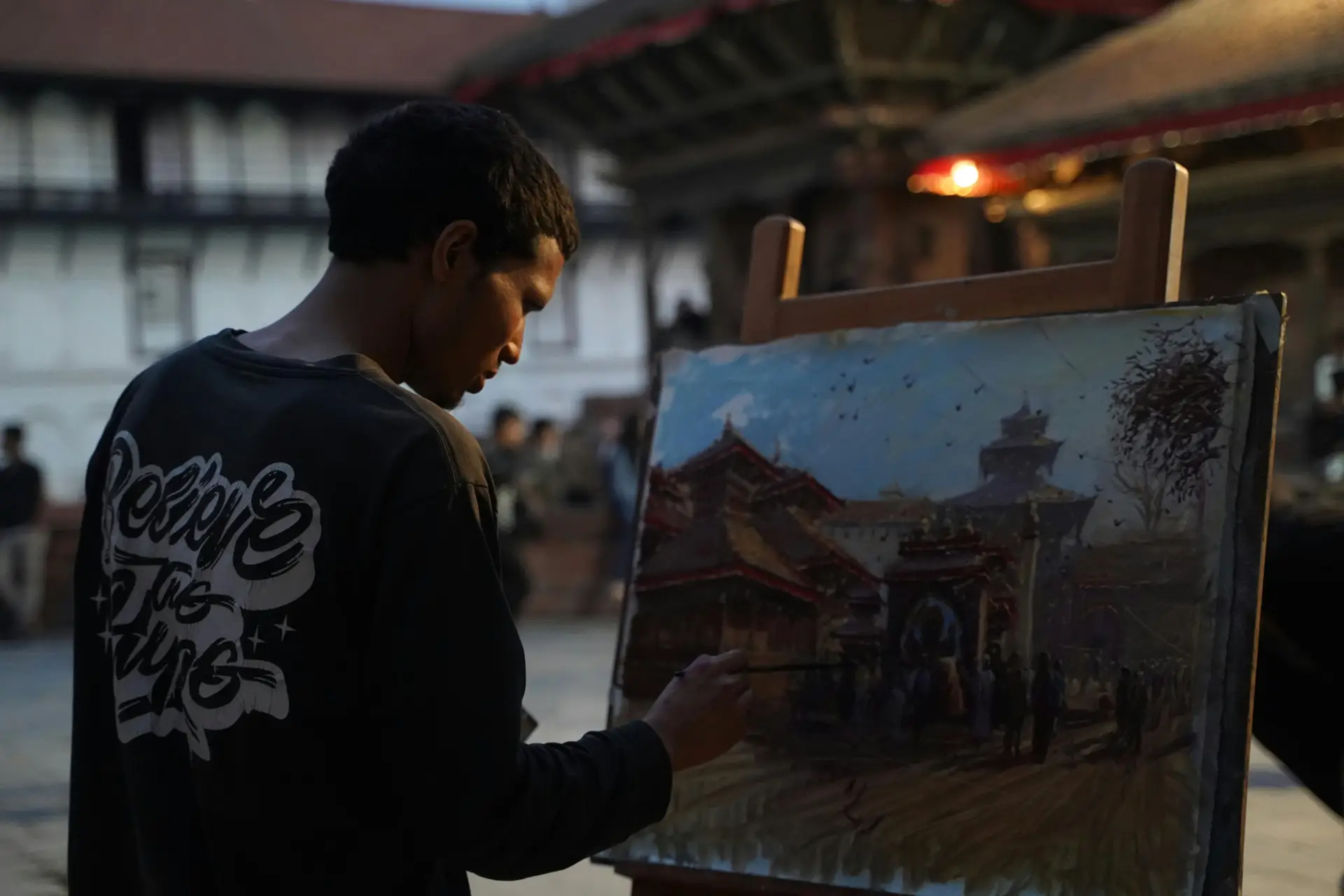 An artist painting a scene at twilight in Kathmandu's Durbar Square, Nepal.
