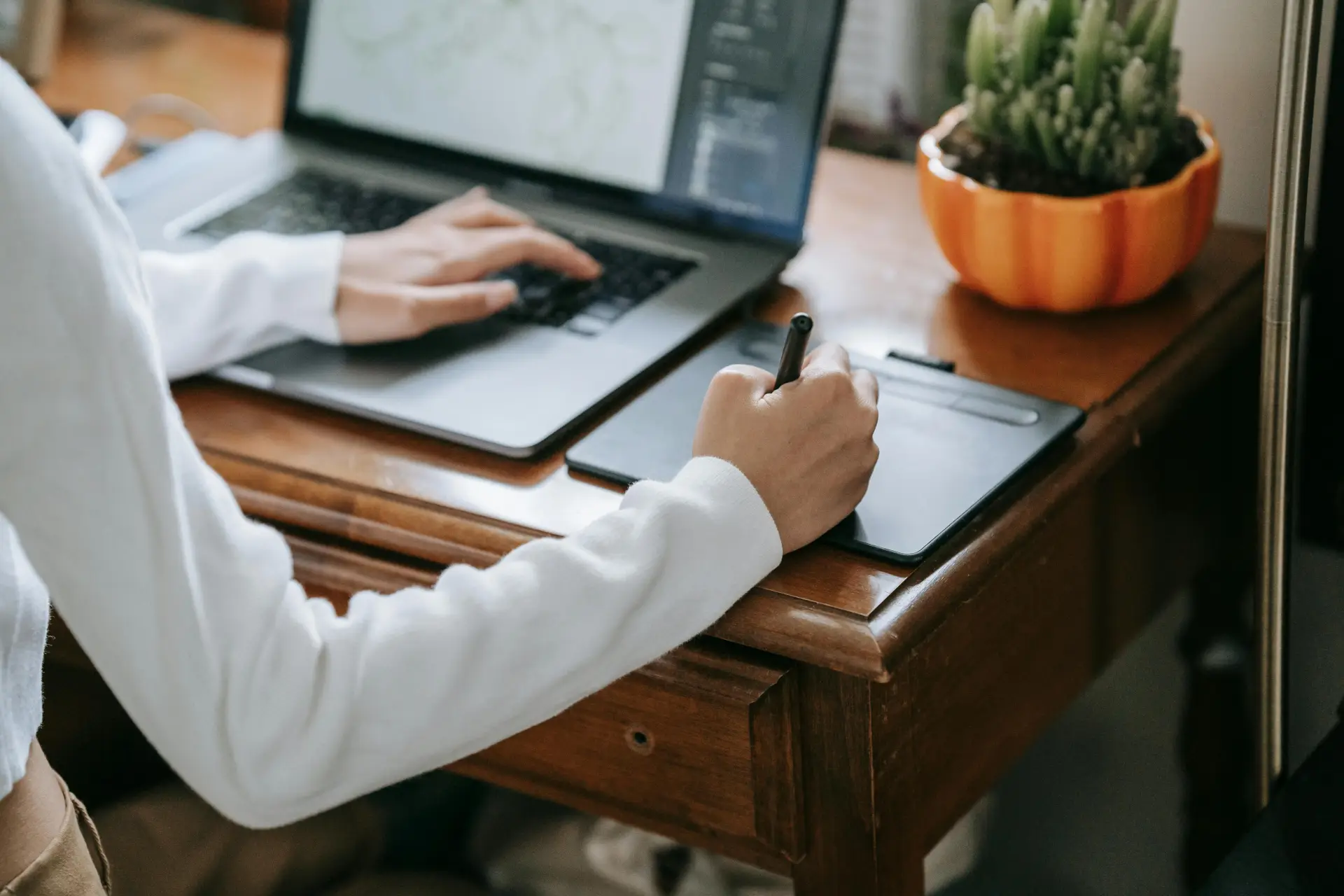 Close-up of designer working on graphics tablet with laptop, enhancing creativity and digital work.
