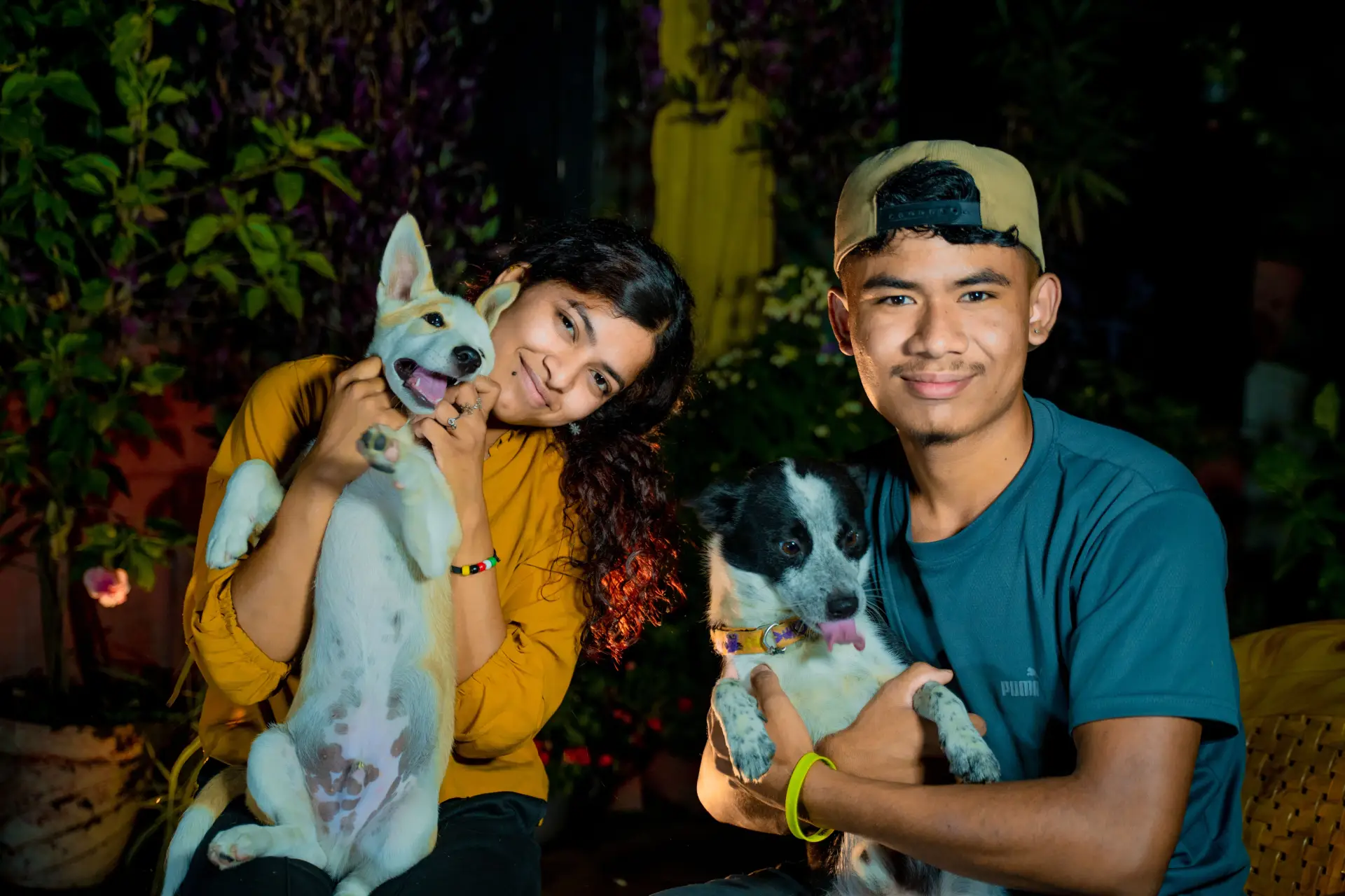Young couple posing with their smiling dogs in an outdoor setting.

