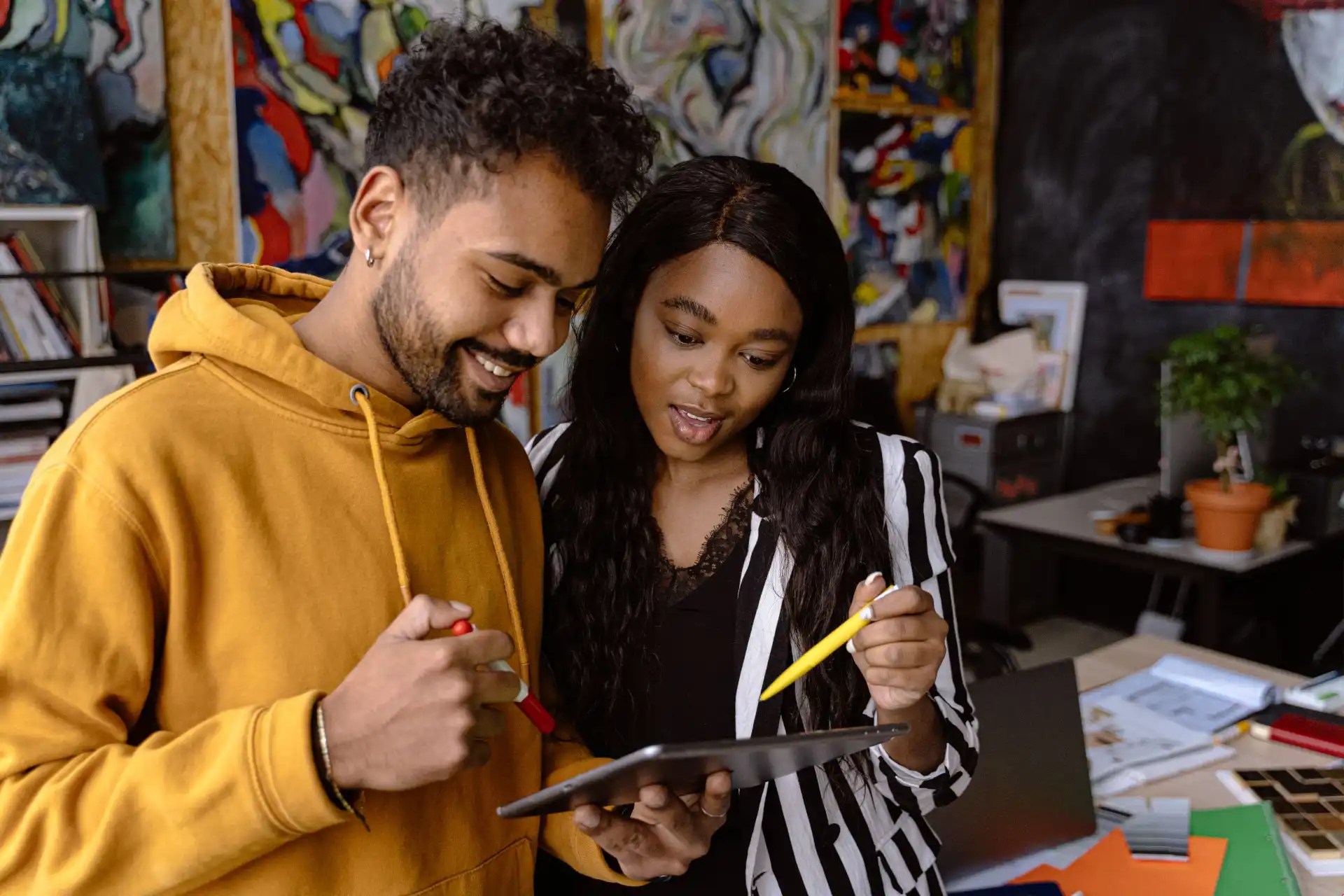 Two colleagues collaborate in a vibrant office using a digital tablet.
