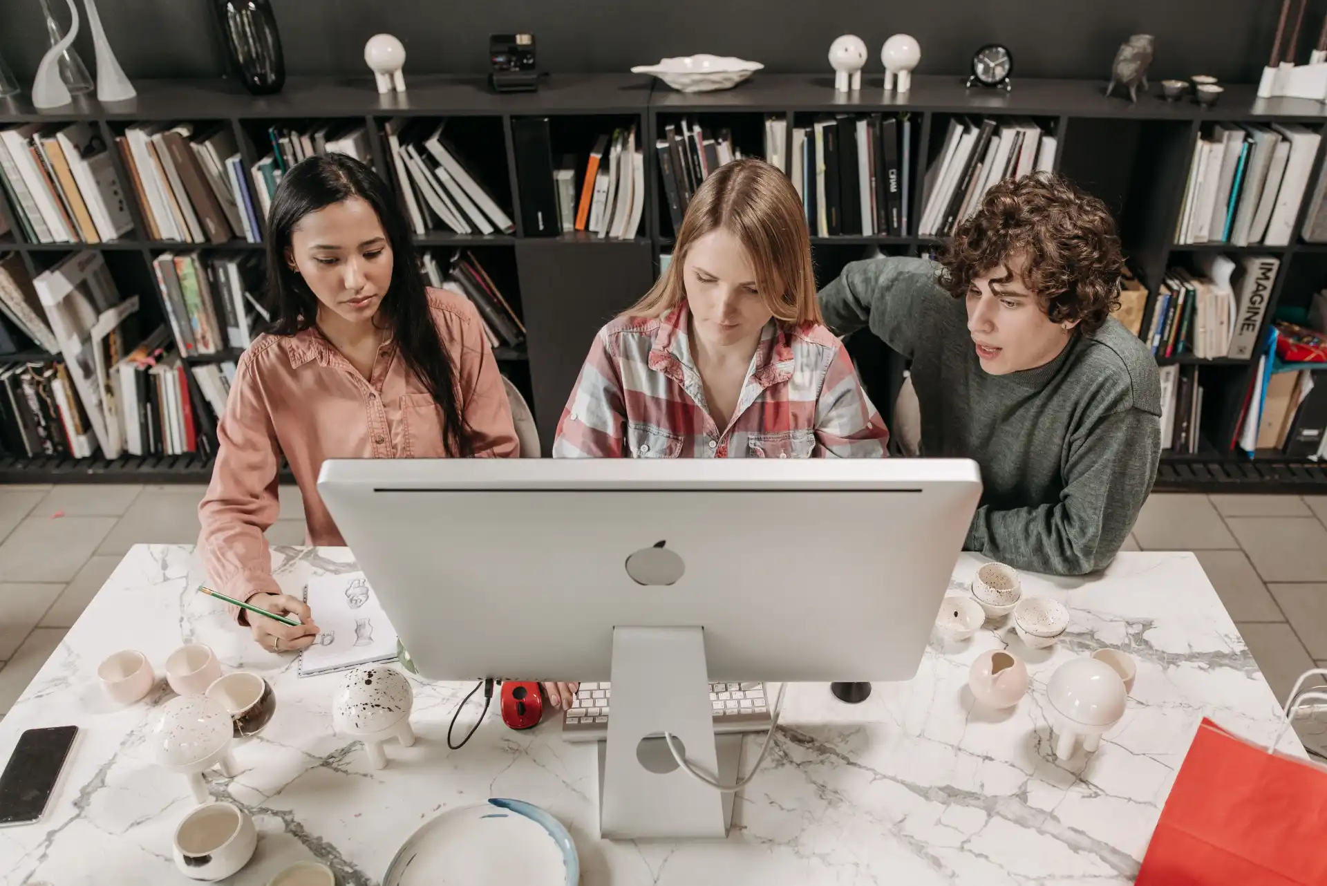 Three colleagues collaborating on a project in a modern office setting.
